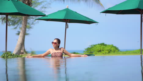 Joven-Asiática-Con-Gafas-De-Sol-Relajándose-En-La-Piscina-Sola