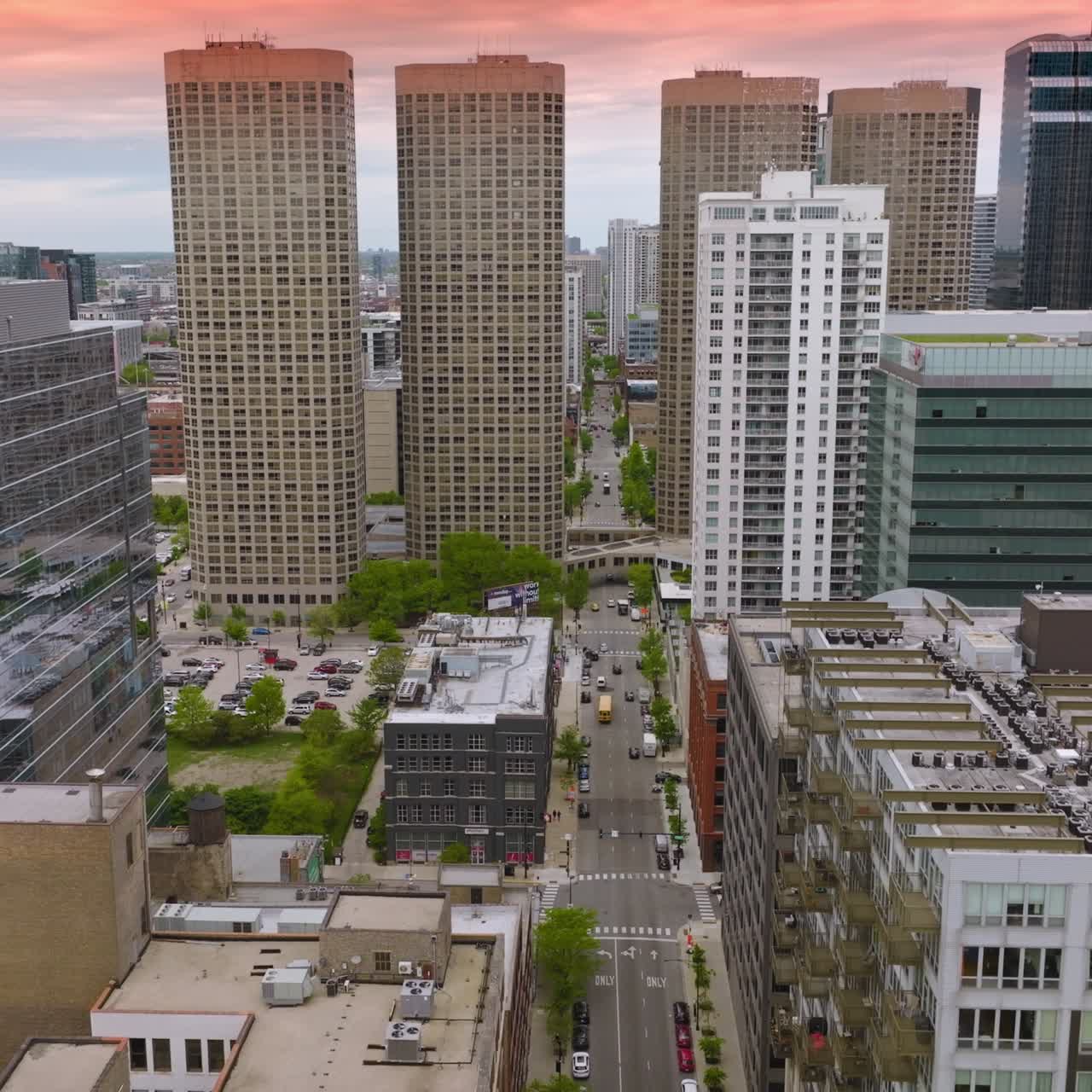 Wide road going through the street among modern buildings. Futuristic architecture of Chicago at the backdrop of pink skies