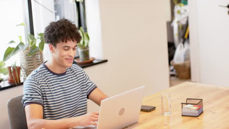 Hombre-Birracial-Trabajando-Desde-Casa-Usando-Una-Computadora-Portátil,-Cámara-Lenta