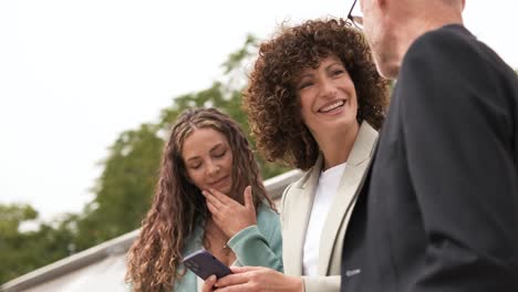 happy businesswoman using cellphone while discussing with coworkers