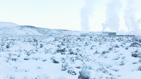 paisaje volcánico cubierto de nieve blanca con vapor saliendo de la central eléctrica