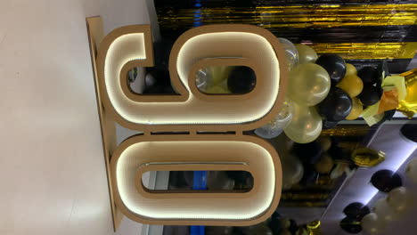 símbolo de cartón del 90 aniversario con luces led con decoración negra y dorada en el fondo
