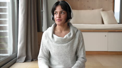 woman meditating at home wearing headphones, finding peace and relaxation