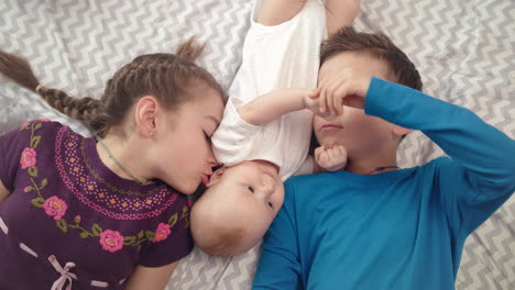 tres hijos juntos. retrato de hermanos felices besando a su hermano pequeño