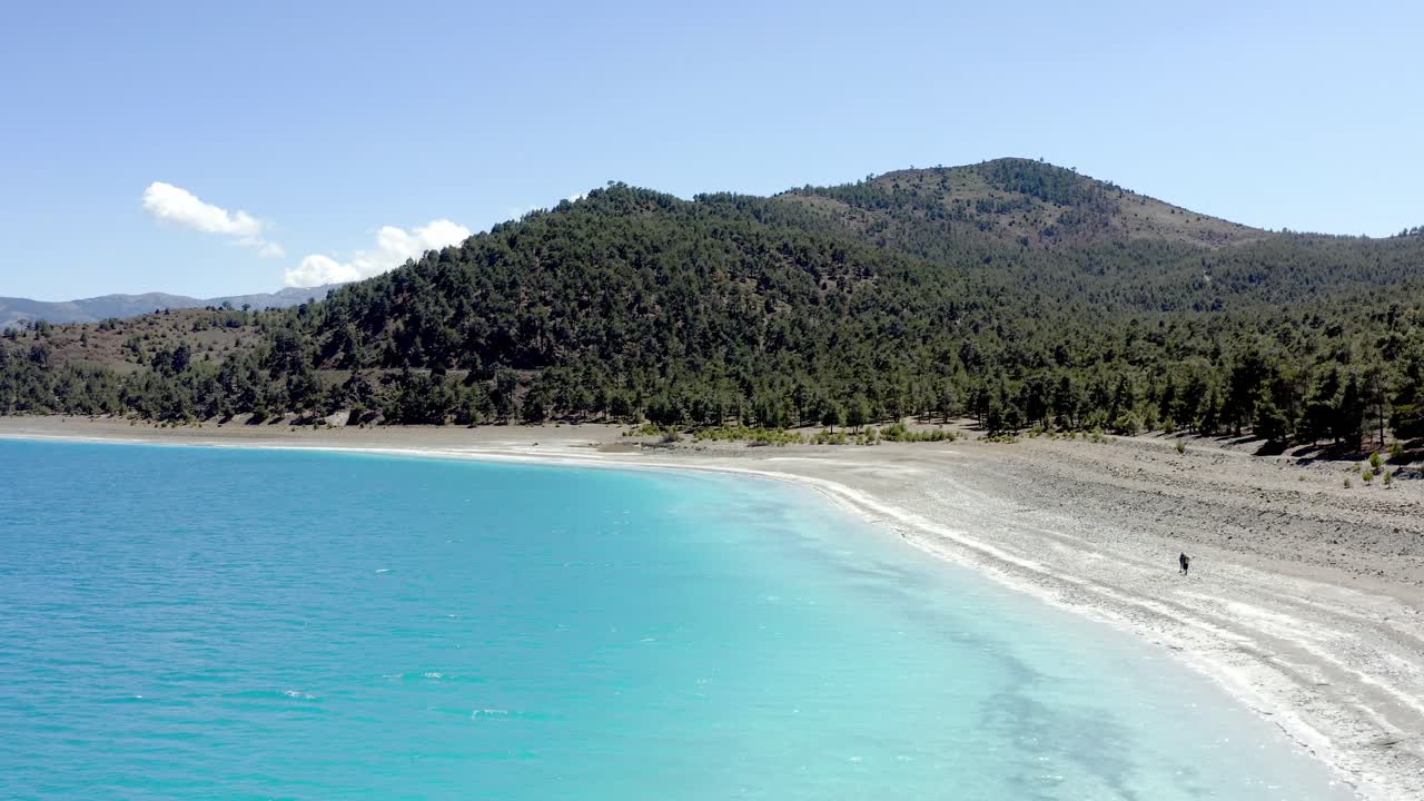 Drone shot along the turquoise water and white shoreline of Lake Salda