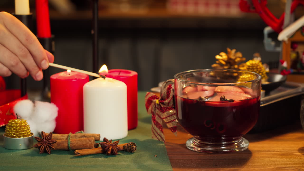 Weihnachtskerzen anzünden und Glühwein auf festlich gedecktem Tisch