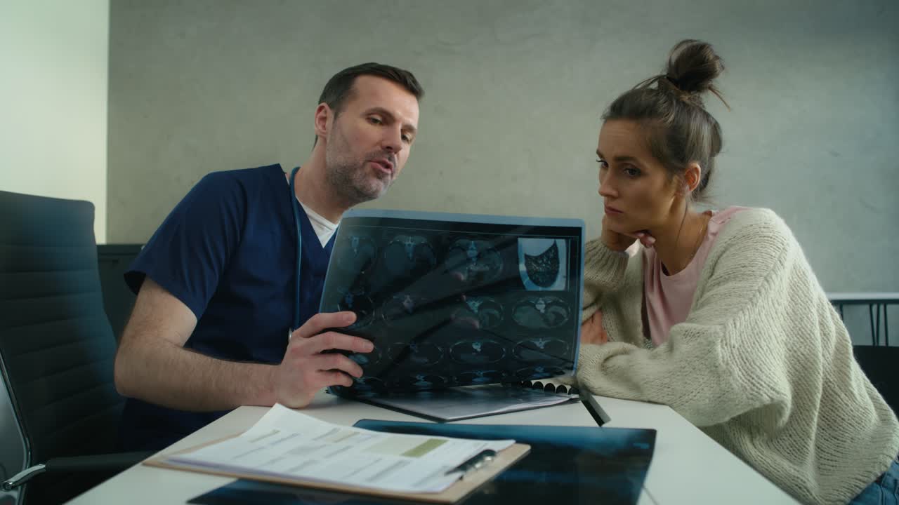 paciente caucásica escuchando el diagnóstico de la resonancia magnética de un médico caucásico masculino