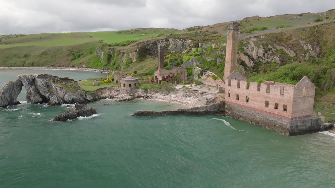 Porth Wenin tiilitehdas, Anglesey, Wales. Näkymä rannikon puolelta hylätystä alueesta rapistuvine rakennuksineen, mehiläispesäuuneineen ja savupiippuineen.