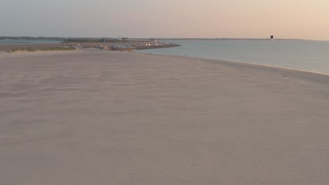 drone cinemático - toma panorámica aérea de la playa natural verde y arenosa al atardecer con buggykiting en zelanda en el mar del norte, países bajos, 25p