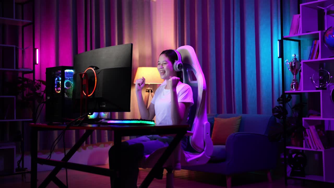 una adolescente asiática emocionada celebra la victoria mientras juega videojuegos en la computadora