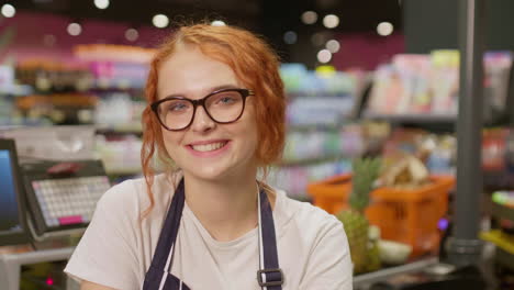 joven empleada de ventas sonriendo y mirando a la cámara en un supermercado