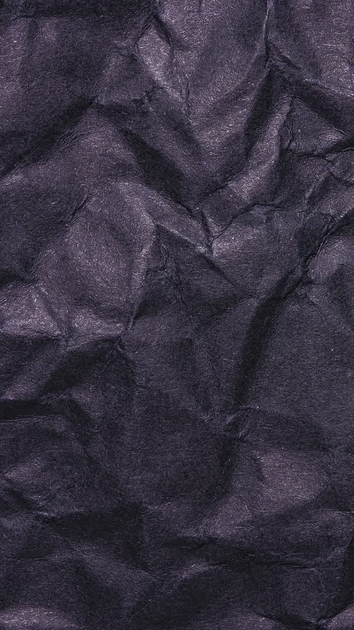 Stop motion verticale di una texture di carta nera stropicciata, loop continuo.