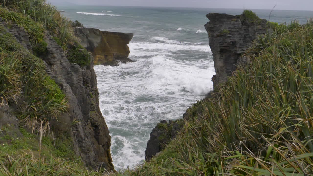 olas en movimiento lento se estrellan entre acantilados - punakaiki, nueva zelanda