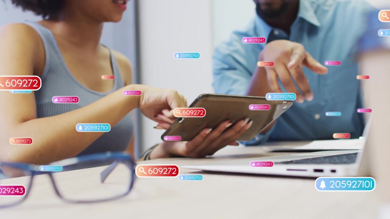 Woman tapping tablet and man pointing laptop, causing animated badges highlighting business data