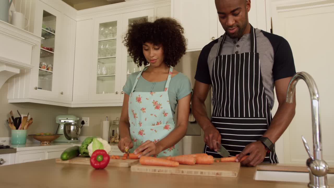 Happy mixed race couple cooking and dancing in their kitchen