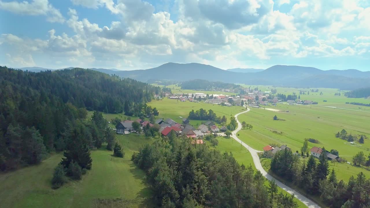 Widok z lotu ptaka na białe chmury nad miastem lub wioską z krętą drogą w Cerknicy, Słowenia