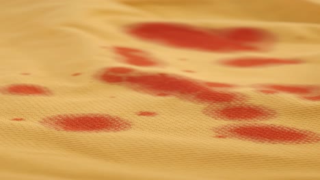 close-up of red blood stains on yellow fabric