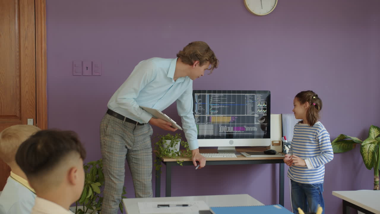 Young Teacher Asking Schoolgirl about Coding Screen at Class