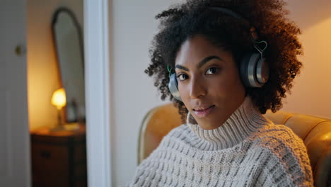 Relaxed-woman-posing-camera-evening-room-portrait.-Dark-skin-lady-in-headphones