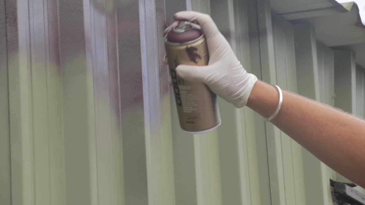 rociar pintura en aerosol graffiti en un edificio metálico
