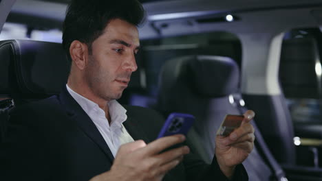 businessman making mobile payment in car