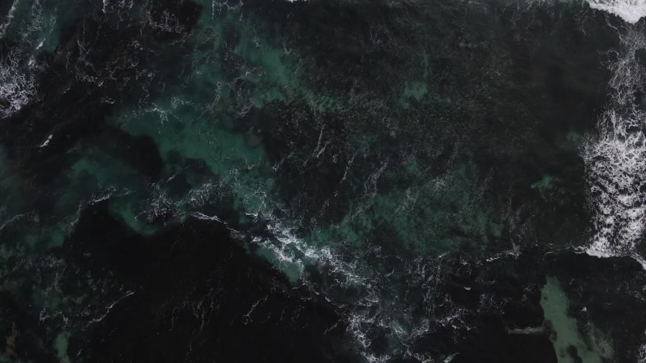 A bird's eye view footage of the open waters with various waves and sea foam