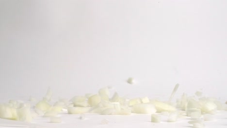 diced white onion pieces falling and bouncing on white table top in slow motion