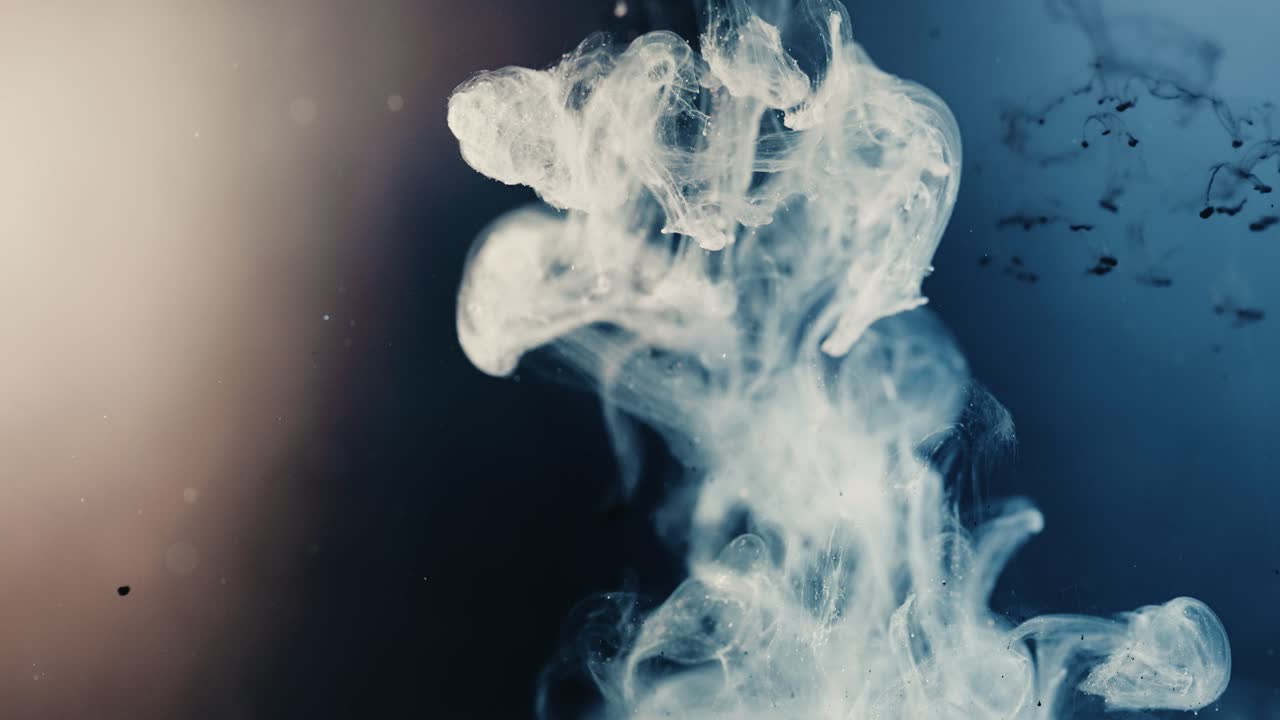 맑은 물에 흰 연기 같은 액체가 떨어지고 있습니다. 매크로