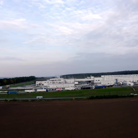 modern manufacture on field. white buildings of large industrial plant near the road in the countryside. camera moving to the right.