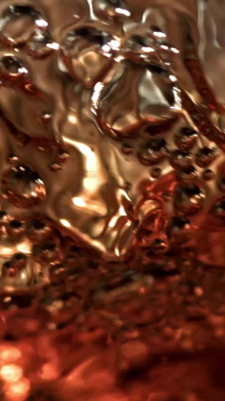 Primo piano dinamico di liquido ambrato effervescente con riflessi di luce