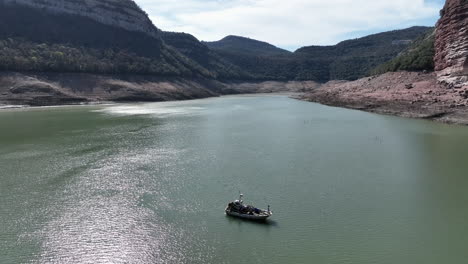 Aerial-view-of-Fisherman-motor-boat-fishing-in-Sau-Reservoir-swamp,-drought