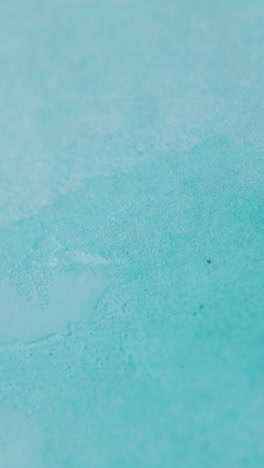 spraying clean liquid from white plastic dispenser onto light blue paper sheet extreme close view