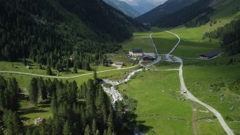 Vista-Aérea-De-Drones-Desde-El-Valle-De-Lüsens-Con-La-Antigua-Posada-De-Lüsens-Y-Las-Altas-Montañas-De-Austria-Al-Fondo-En-Verano