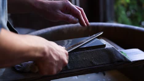 person meticulously sharpening a knife outdoors