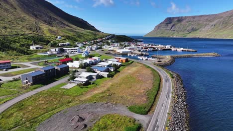 aerial view of sudureyri, iceland, fishing village, fjord, buildings and port on sunny day