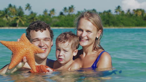 Padres-E-Hijo-En-Agua-De-Mar-Sosteniendo-Estrellas-De-Mar