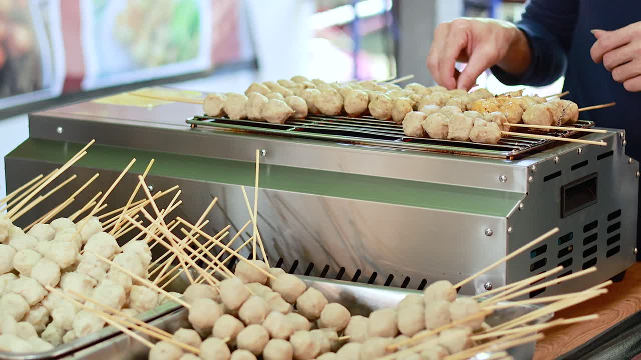 vendedor callejero asando albóndigas en pinzas en bangkok