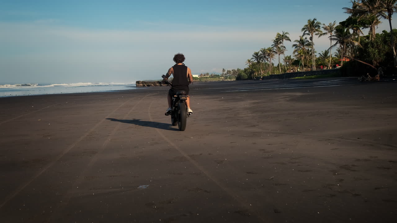 Man Riding Motorcycle on a Black Sand Beach