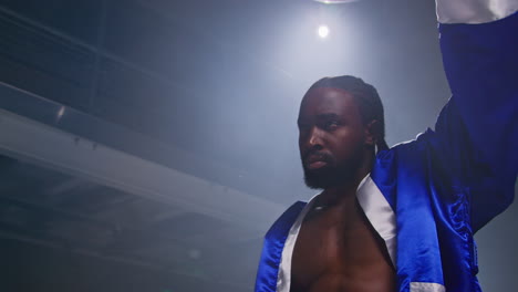 a boxer in a blue robe stands in the ring, ready to fight