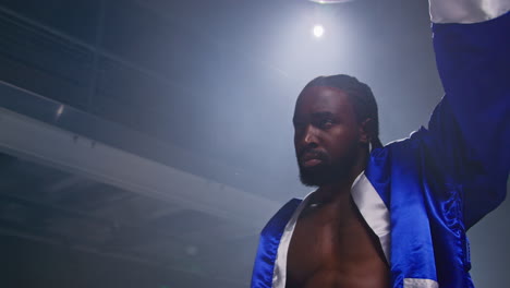 un boxeador con una túnica azul está en el ring, listo para luchar