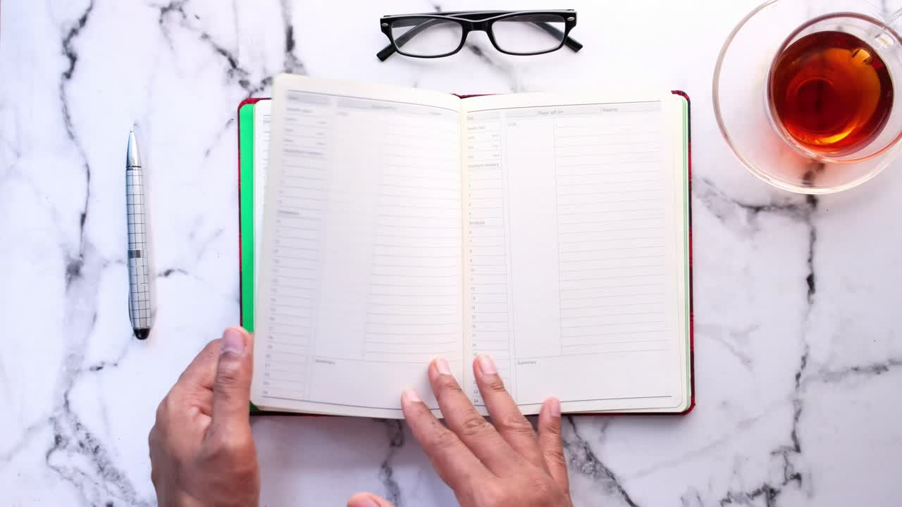 persona que planea con un cuaderno, té y gafas