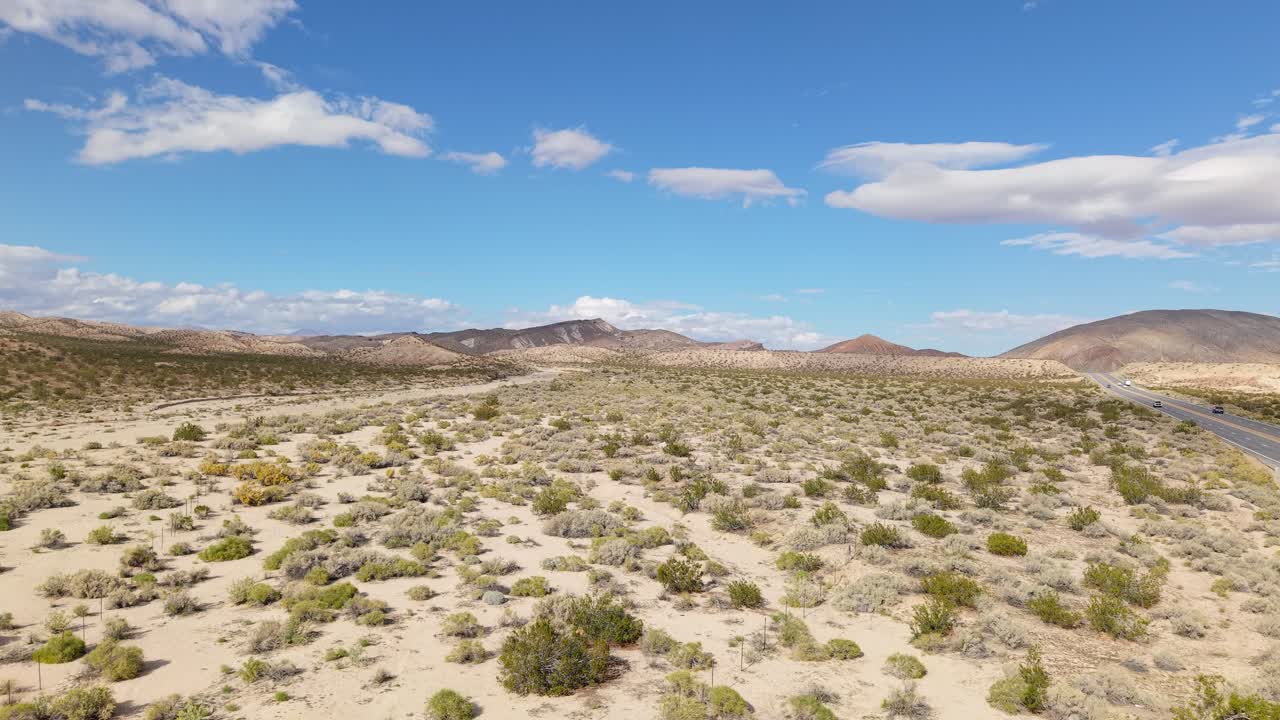 Droneopptak i stigende vinkel som avslører de dramatiske mesaene i Red Rock Canyon, omgitt av myk ørkenvegetasjon og åpen himmel