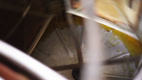 close up of fresh liquid dense honey extractor machine spinning, honeycomb hive frames turning around, traditional apiculture bee honey extraction-production in farm