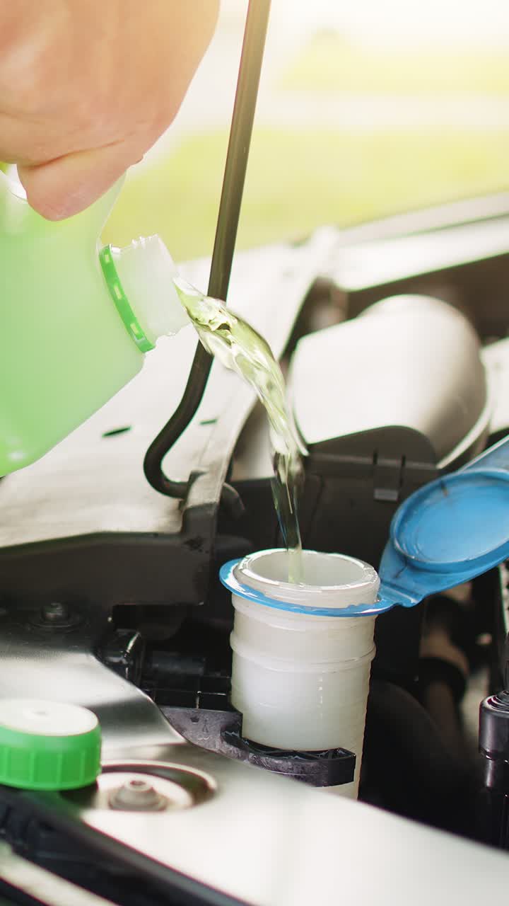 서비스 직원 남자는 자동차 앞유리 녹색 청소 세탁기 유리 여름 또는 겨울 청소기를 붓습니다