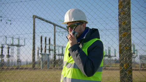 Ingeniero-Masculino-Hablando-Por-Radio-En-La-Subestación-Eléctrica,-Dinámica-Portátil