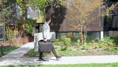 Male-floor-plan-technician-walks-happily-towards-contemporary-home