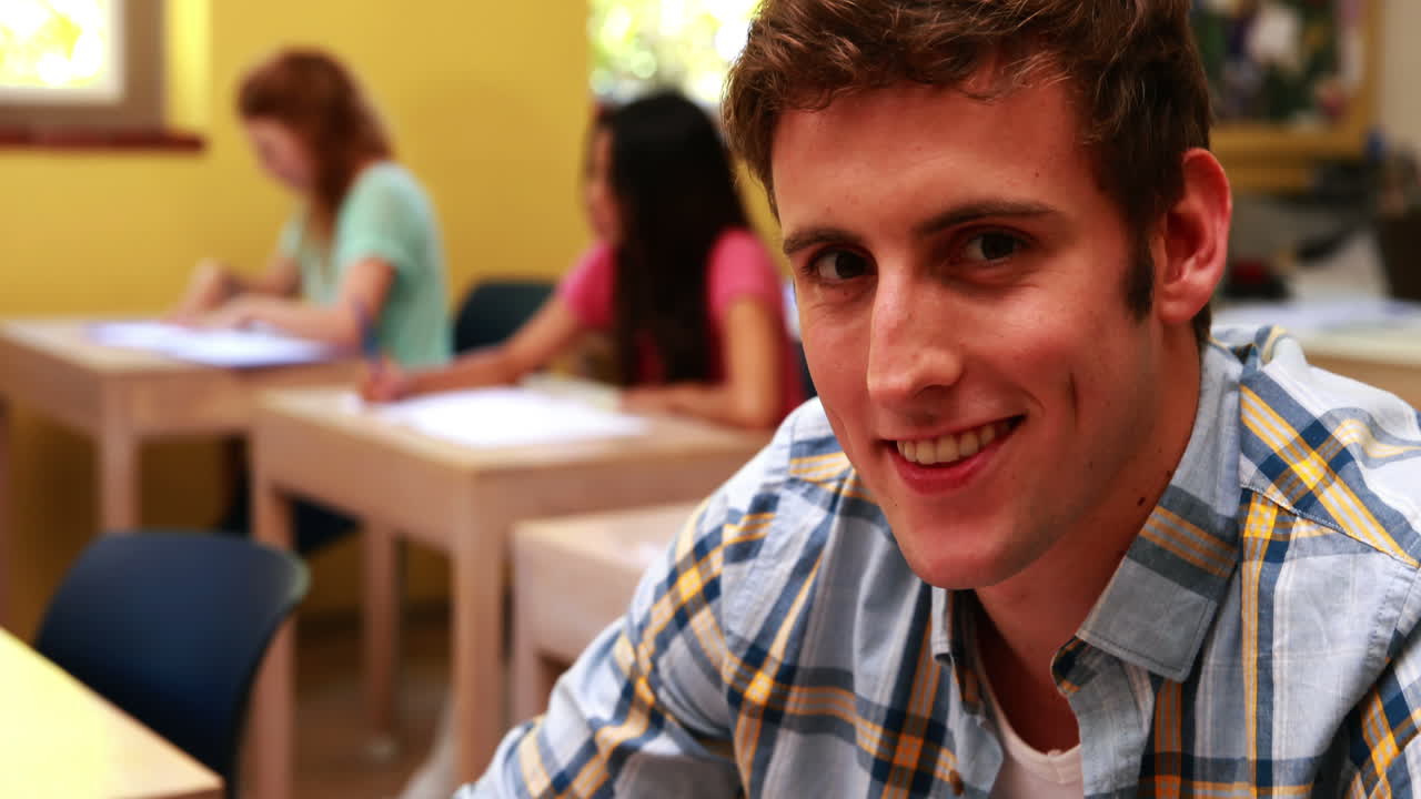 estudiante guapo sonriendo a la cámara en el aula