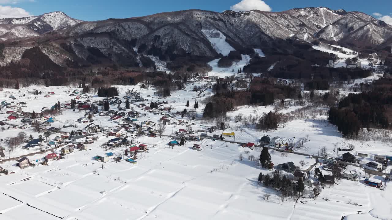 Aerial drone view of snow-covered rice fields and village in Nagano, Japan