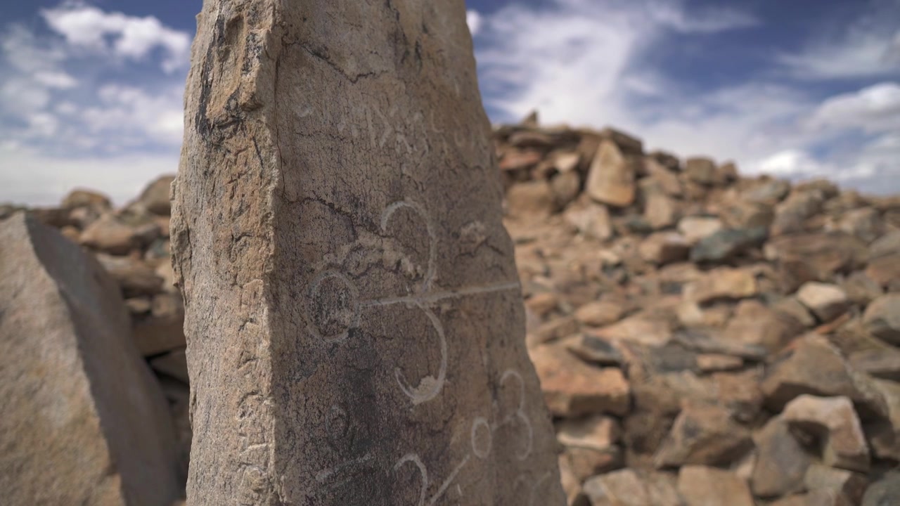 Antica stele di pietra con petroglifi in un paesaggio roccioso