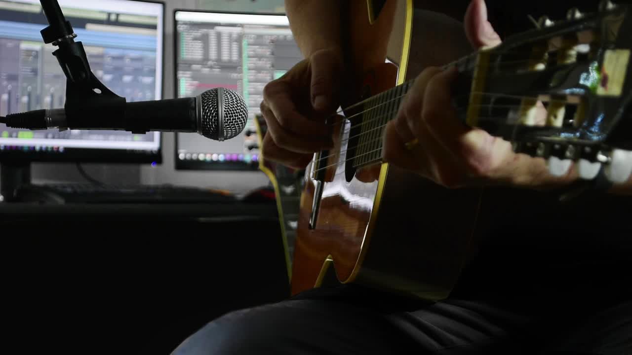 guitarrista clásico graba con un micrófono en un estudio de grabación en casa, usando software de pc